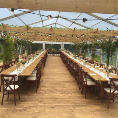 Clear Roof Marquee With Hired Tables and Chairs with Wooden Floor - 9m x 30m full clear roof and side marquee holding a beautiful rustic interior.